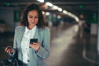 A woman uses her mobile phone to start parking and charging in the same app, APCOA FLOW, easily and stress-free inside the car park. 