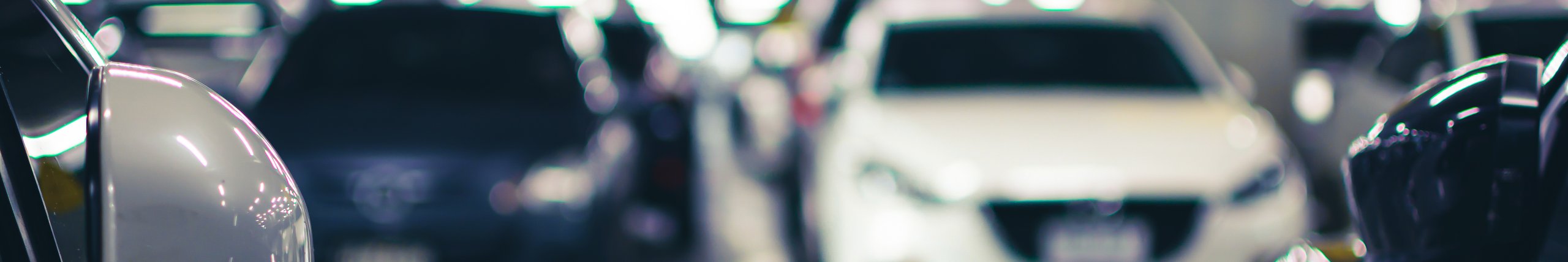 Moderne og godt opplyst parkeringshus med parkerte biler.